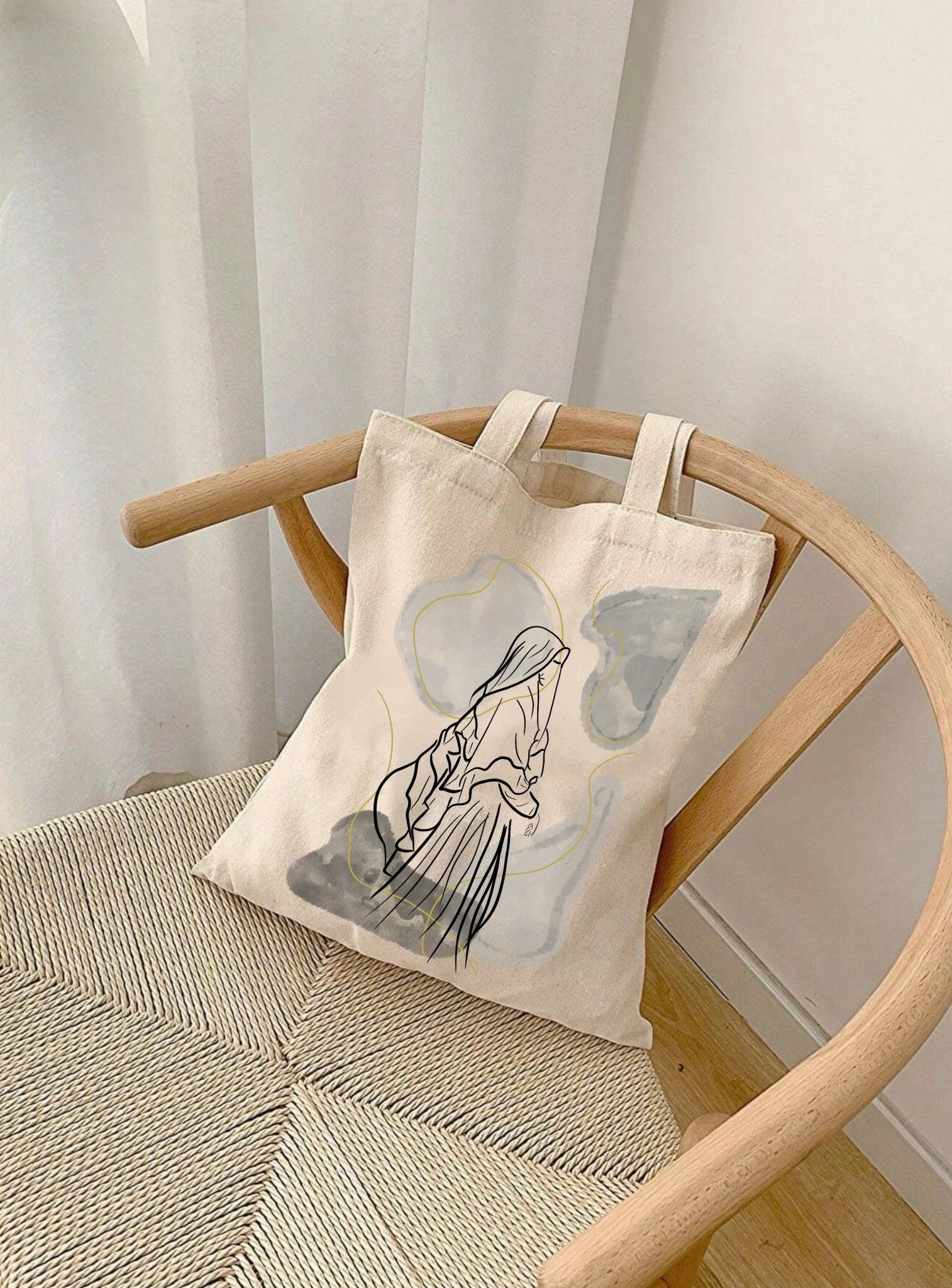 sac en toile Seni'Stuff avec illustration minimaliste, posé sur une chaise près d’un rideau blanc
