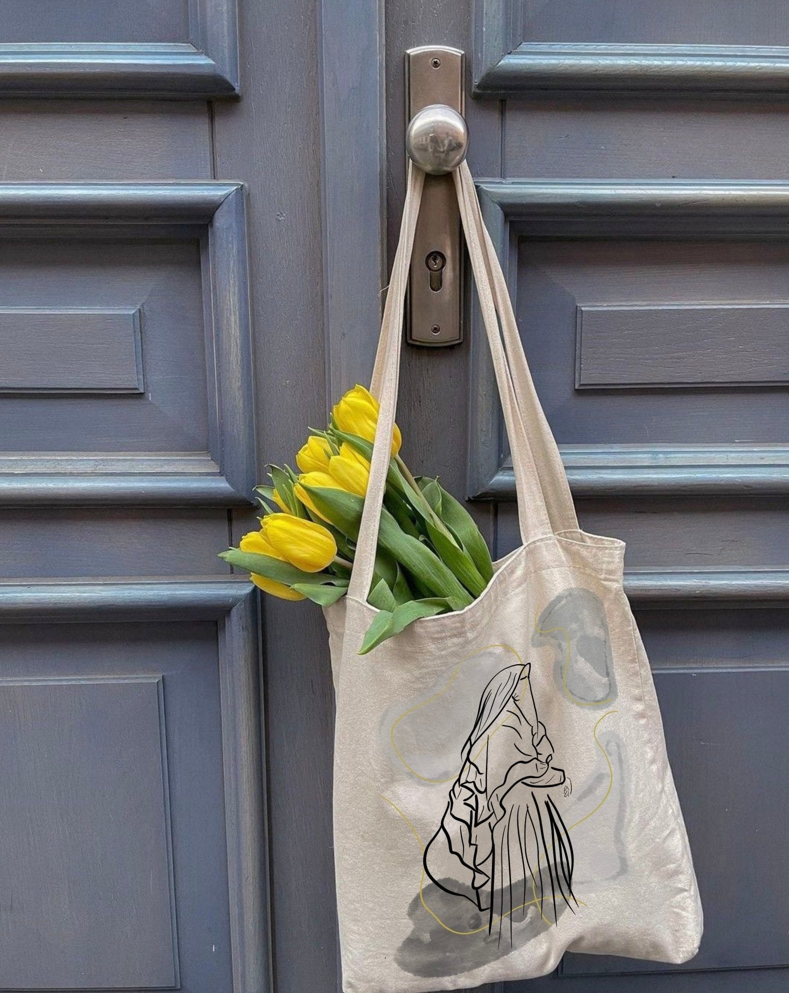 sac fourre-tout Seni'Stuff accroché à une porte avec des tulipes jaunes à l’intérieur