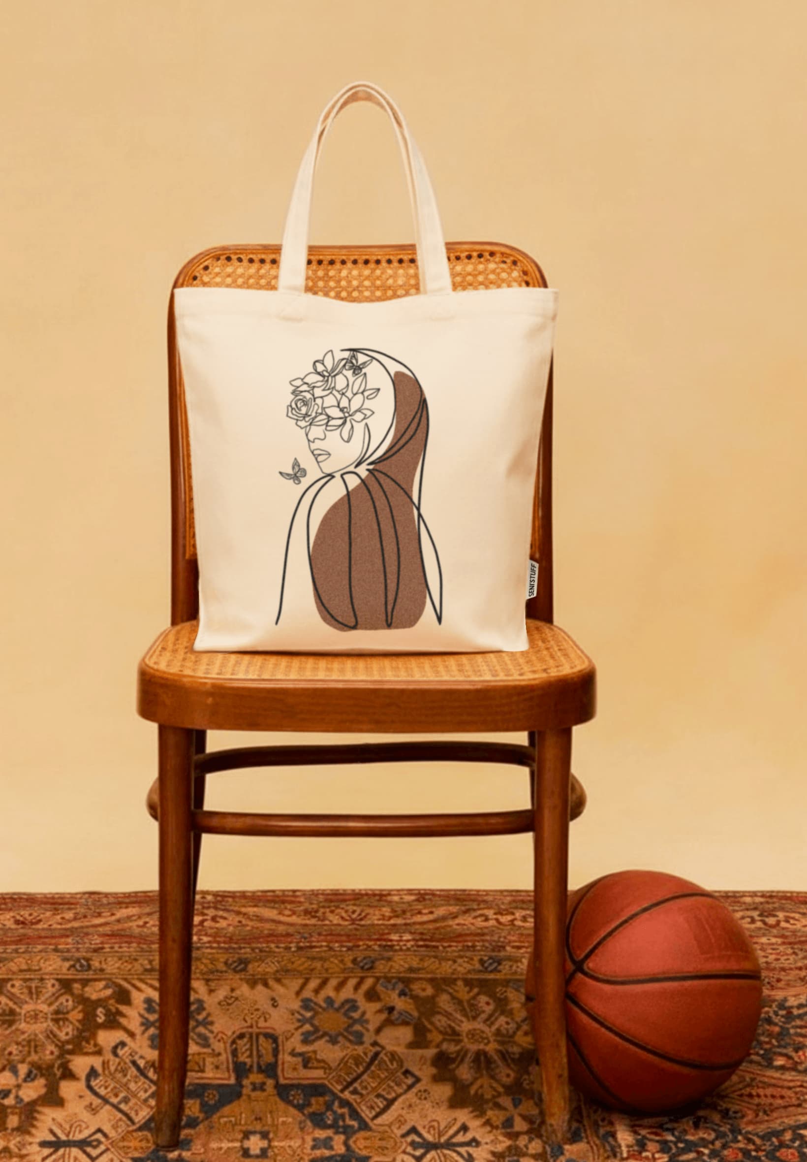 Tote bag Seni'Stuff posé sur une chaise en bois devant un fond beige, à côté d’un ballon de basket vintage sur un tapis oriental.